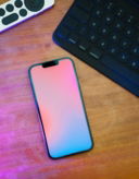 a-cell-phone-sitting-on-top-of-a-wooden-table-next-to-a-keyboard.jpg A cell phone sitting on top of a wooden table next to a keyboard
